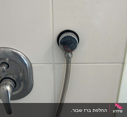 ברז ומקלחת על קיר אריחים לבנים